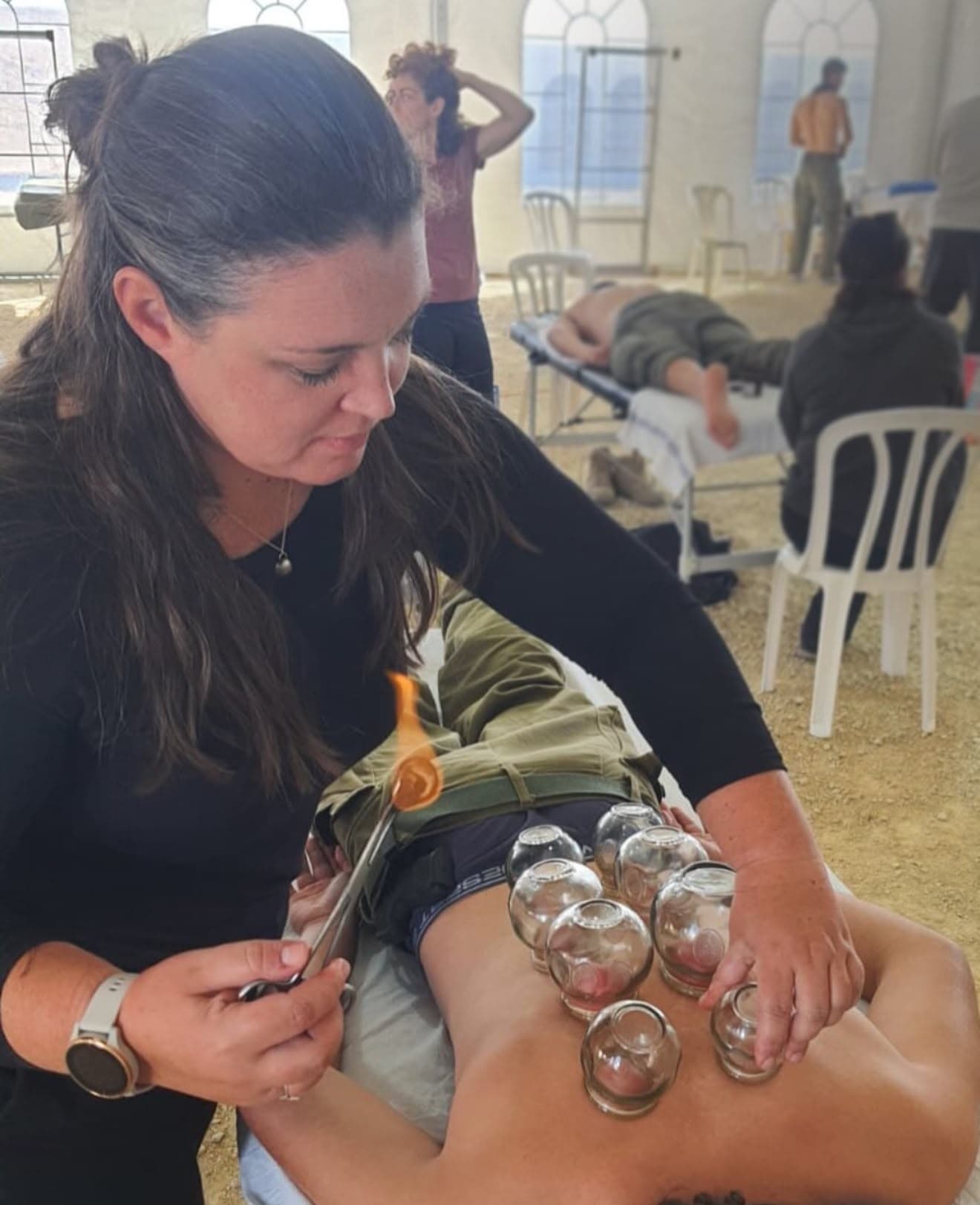 דיאנה קרוק מניחה כוסות רוח על גבו של מטופל